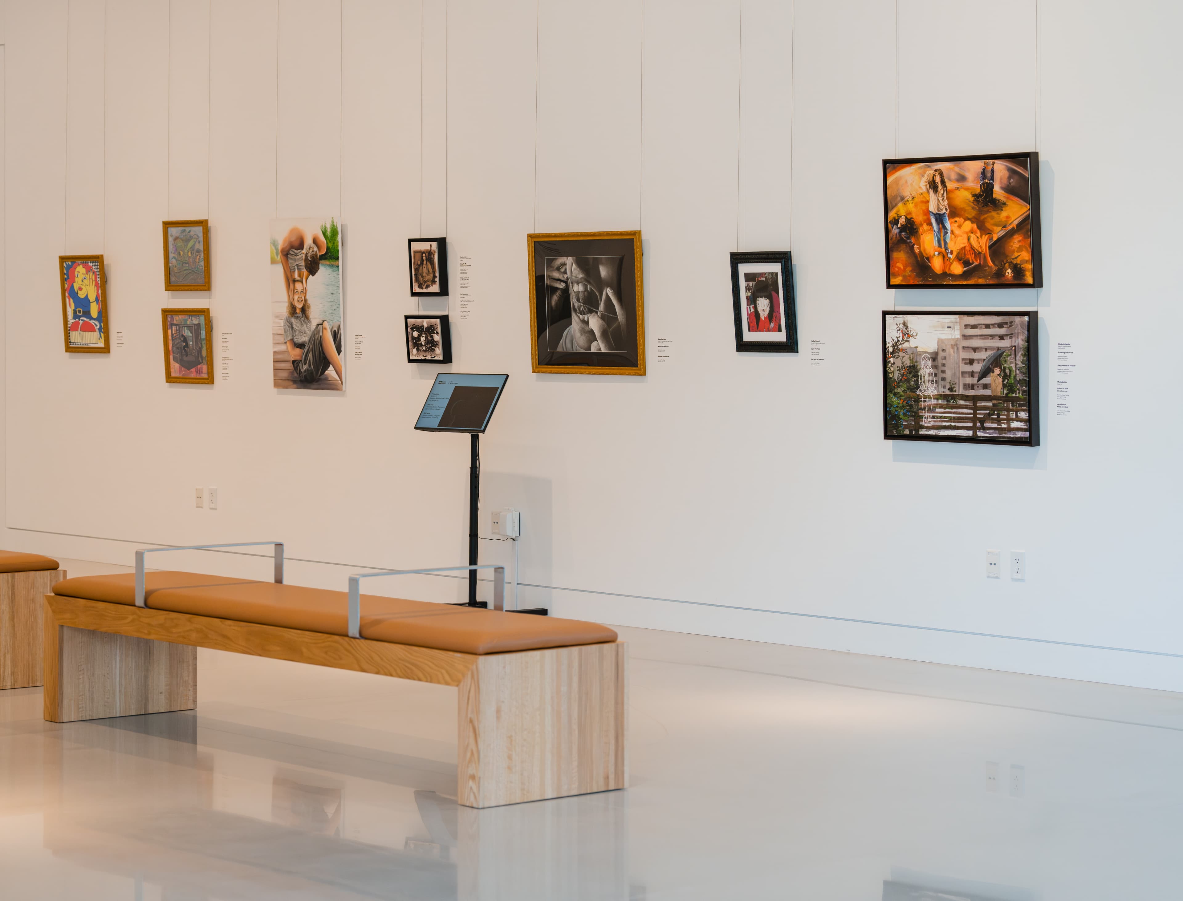 A modern white walled gallery space with benches.