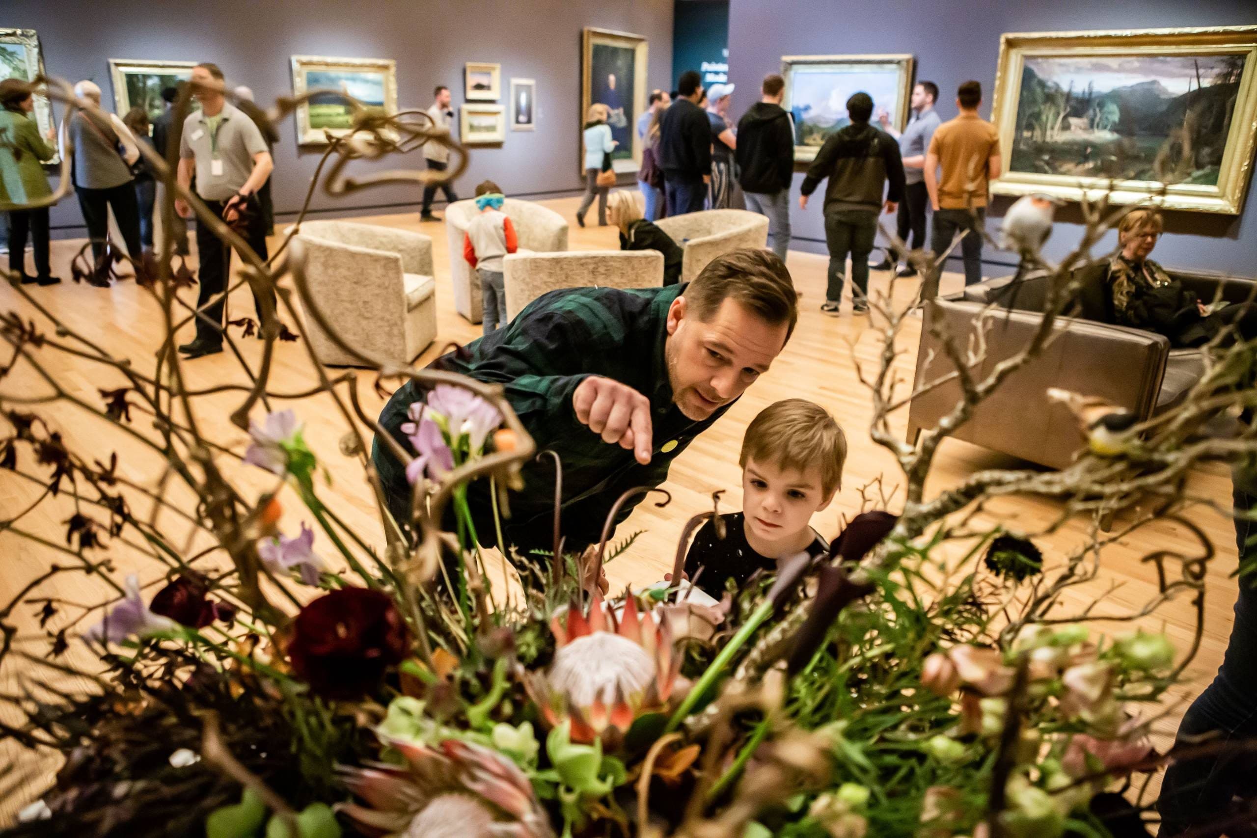 Man and Child Admiring Floral Artwork in Gallery